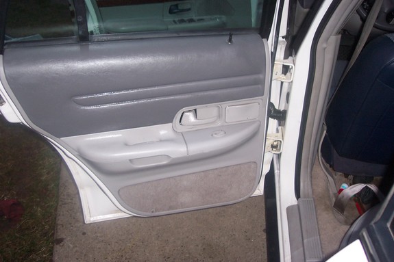 Interior of a car door, showing the gray panel, door handle, and armrest