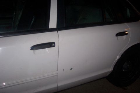 1996 Ford Crown Victoria - Close-up of a white sedan's side, showing door handles, a dent, and the rear tire.