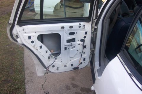 1996 Ford Crown Victoria - The interior of a white 1996 Ford Crown Victoria door, showing exposed wiring and mounting points.