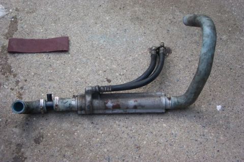 1996 Ford Crown Victoria - An oil cooler assembly with attached hoses lies on a concrete surface next to a piece of sandpaper.