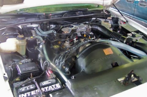 1996 Ford Crown Victoria - Engine bay view showing components like batteries and hoses, with a caution label on the fan shroud.