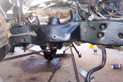 1996 Ford Crown Victoria - Close-up view of a vehicle's frame and suspension components, with a can of WD-40 visible on the ground.