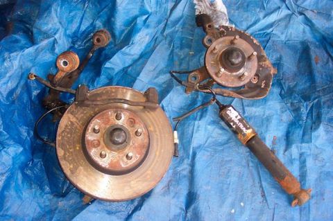 1996 Ford Crown Victoria - Disassembled front suspension components, including a brake rotor and shock absorber, lie on a blue tarp.