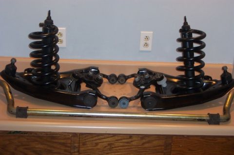 1996 Ford Crown Victoria - Front suspension components, including control arms, shocks, and sway bar, laid out on a counter.