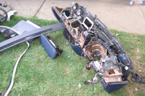 1996 Ford Crown Victoria - A disassembled car dashboard with its internal components and wiring exposed is spread out on a grassy area.