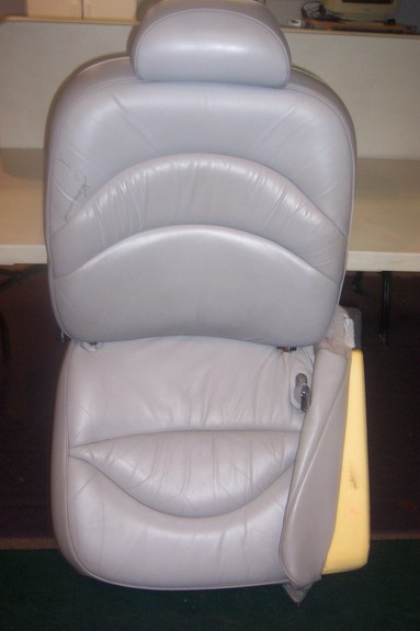 1996 Ford Crown Victoria - A light gray leather car seat, likely from the front row, is shown with its headrest and exposed foam padding on the side.