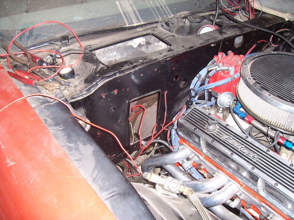 Red car engine bay with black firewall, red fender, and chrome "Edelbrock" valve covers