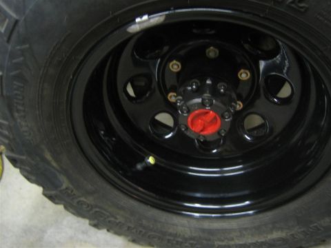 1987 Suzuki Samurai - A close-up view of a vehicle's wheel and tire, a black rim and a red hub assembly.