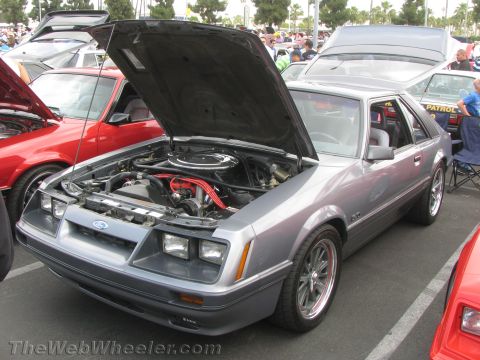 1968 Ford Mustang - A silver Ford Mustang GT from the early 1980s is displayed with its hood open at an outdoor car show.