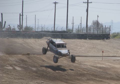 2008 Ford Bronco - A custom off-road buggy soars through the air during a race on a dusty track.