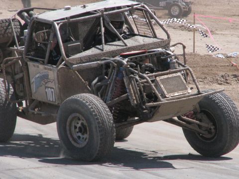 2008 Ford Bronco - A heavily modified off-road buggy competes in a race, kicking up dust as it navigates the track.