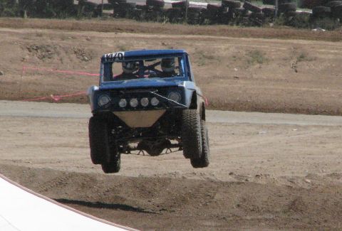 2008 Ford Bronco - Off-road truck with two occupants jumps over a dirt track.