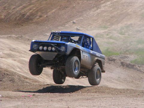 2008 Ford Bronco - This modified off-road vehicle is airborne during a race, kicking up dust on a dirt track.