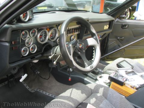 1968 Ford Mustang - The interior of a car features a dashboard filled with gauges and a steering wheel with a "5.0" badge visible.