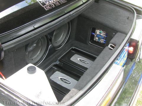 1968 Ford Mustang - Custom car trunk setup dual subwoofers and twin amplifiers, with visible wiring and a fluid reservoir.