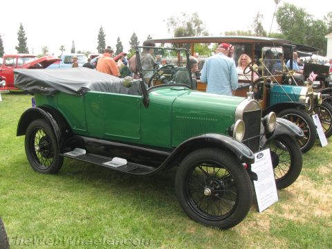 1968 Ford Mustang - A green touring car with a black top and fenders is parked on a grassy field next to other vintage vehicles.