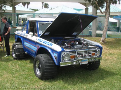 1968 Ford Mustang - Modified Ford Bronco with custom paint and oversized tires, engine exposed under the open hood.