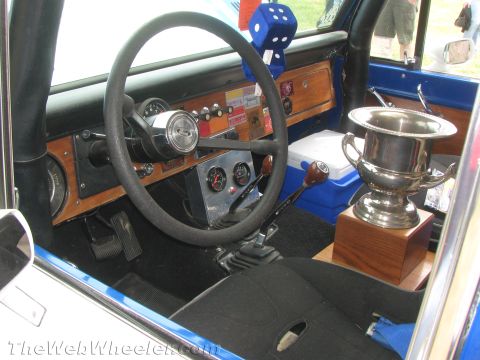 1968 Ford Mustang - The interior of a vehicle features a trophy, dice hanging from the rearview mirror, and a wooden dashboard.