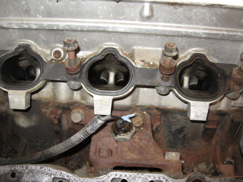 Close-up of engine intake ports on an aluminum head with bolts