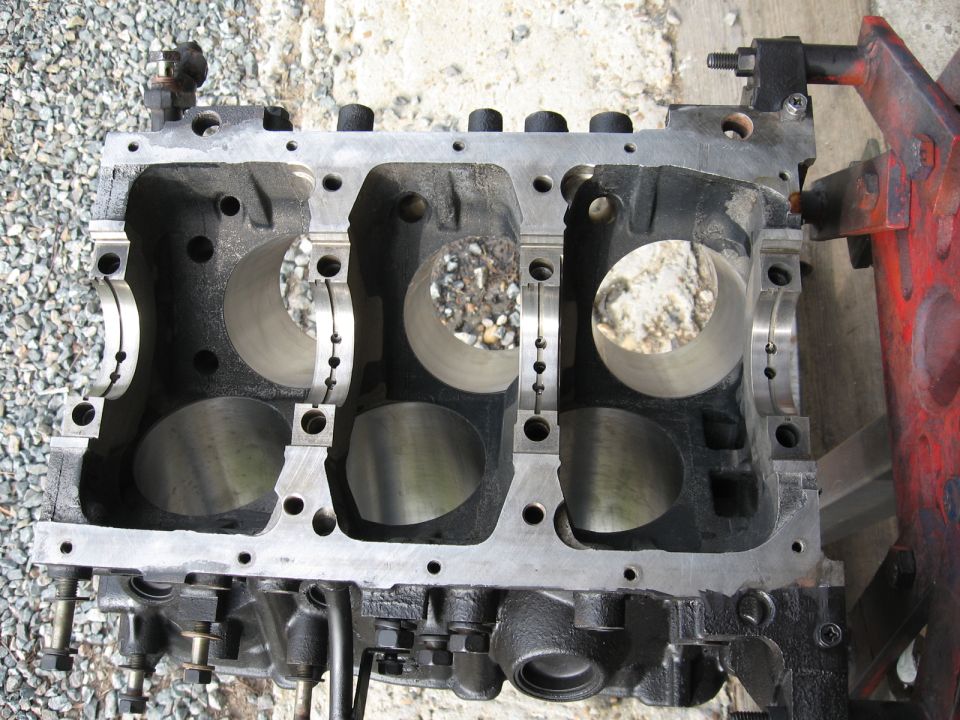 V6 engine block with six cylinder bores outdoors on gravel
