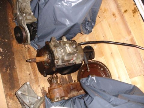 1996 Ford Bronco - Transmission and transfer case components are laid out on a wooden floor, partially covered by plastic bags.