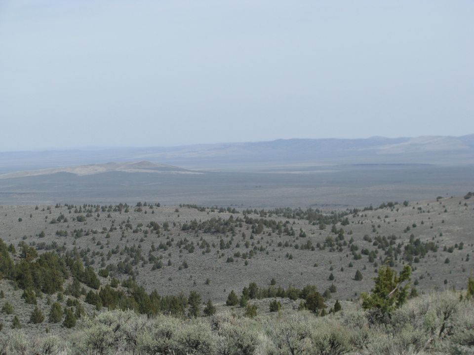 High-desert overlook with junipers, sagebrush and hazy distant ridges