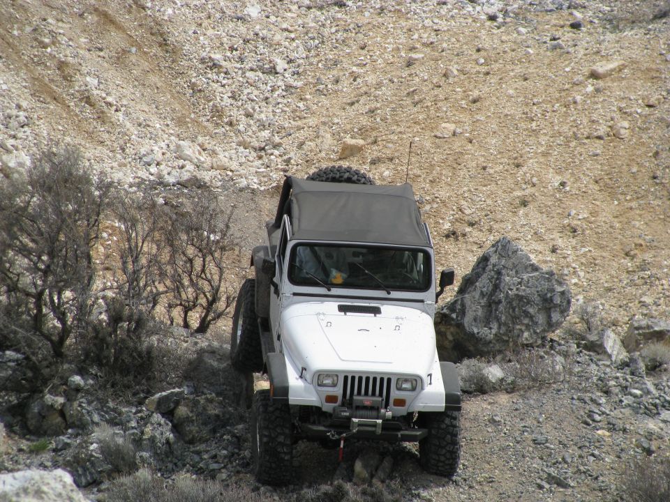 White Jeep Wrangler YJ with Warn winch descending rocky desert trail, overhead view