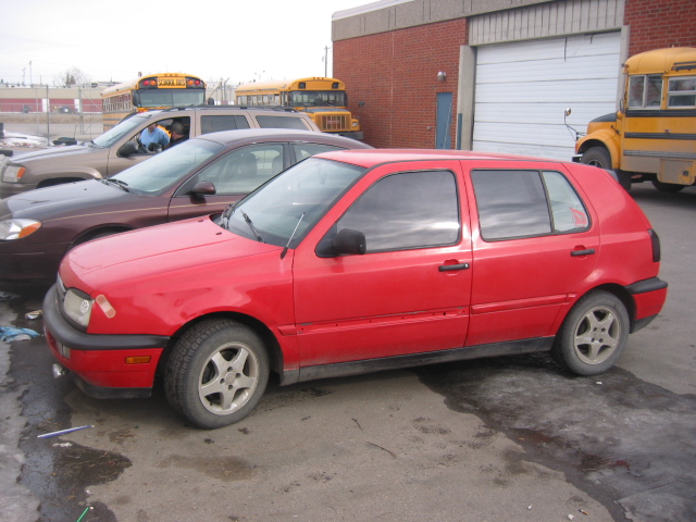 Red 1995 Volkswagen Golf hatchback parked on a lot.