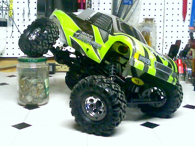Green and black RC monster truck on a jar of coins.