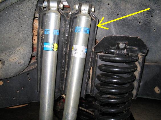 Close-up of vehicle suspension with two Bilstein shocks and a coil spring.