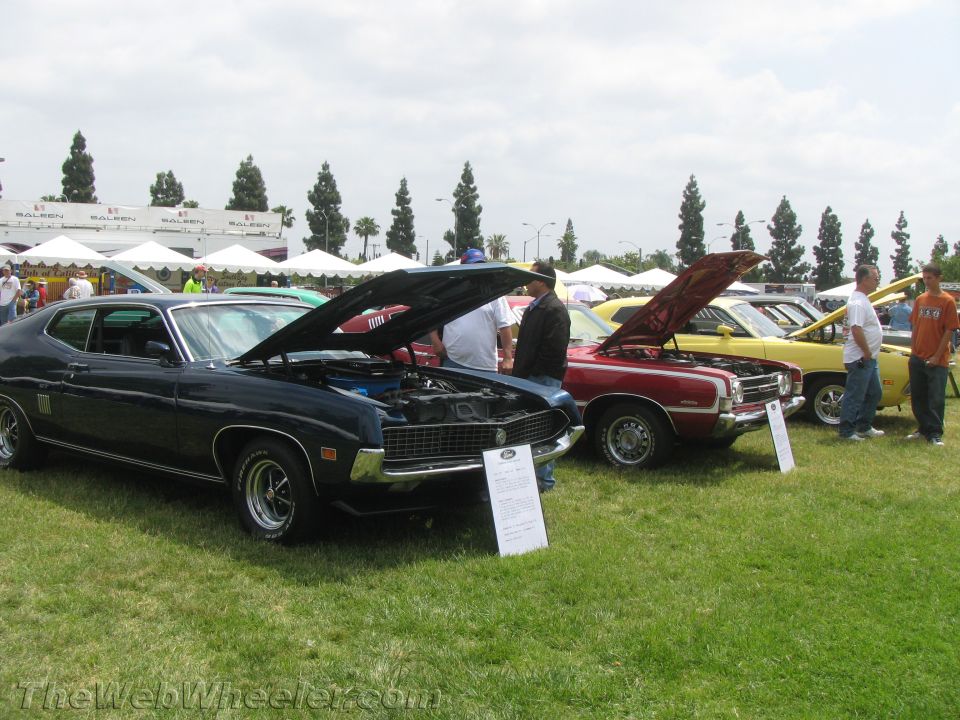 Black and red 1970s Ford Torino muscle cars with hoods open at a car show