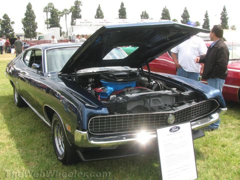 1968 Ford Mustang - Photograph of a dark blue Ford Torino displayed at an outdoor car show with its hood raised.