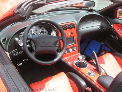 1968 Ford Mustang - Photograph of a custom red-and-black Mustang interior showing steering wheel, gauges and console.