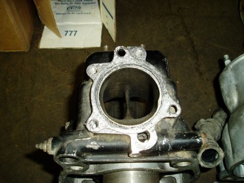 2000 Ford E350 - A close-up view of a black engine part with a silver flange, likely a cylinder head or intake manifold, is shown. In the background, a card…