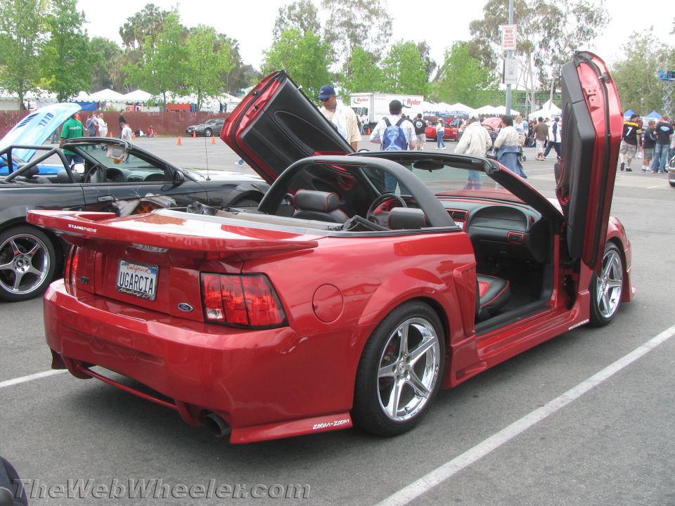 Red convertible car with custom lambo doors and spoiler, viewed from rear-right