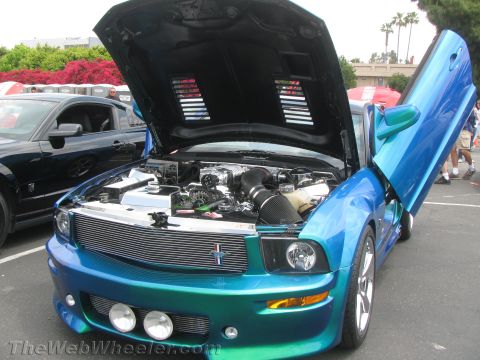 1968 Ford Mustang - This modified Mustang features custom butterfly doors and a visible engine, with another Mustang in the background.