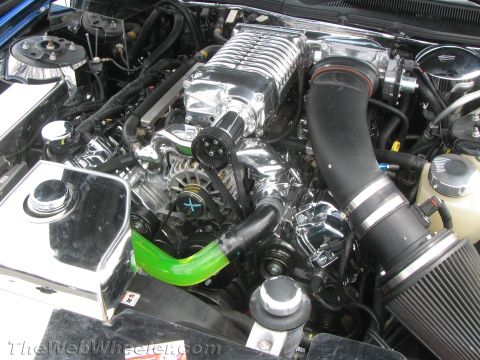 1968 Ford Mustang - Close-up view of a modified engine bay a prominent supercharger and custom hoses.