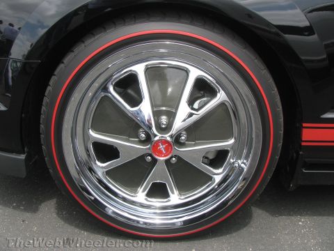 1968 Ford Mustang - A close-up shot focuses on the chrome wheel and red-striped tire of a black Ford Mustang.