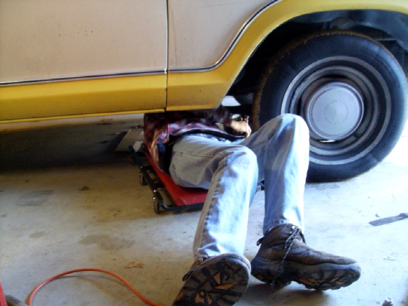 Person working under a yellow and white pickup truck.