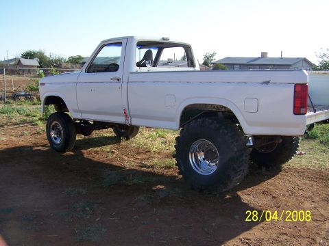 1995 Ford Bronco - A lifted white pickup truck with large off-road tires is parked on a dirt lot under a clear blue sky. The truck has a single cab and a long…