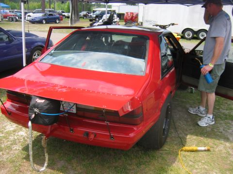 1992 Ford Mustang - A red drag car is parked on grass with a parachute attached to its rear spoiler.
