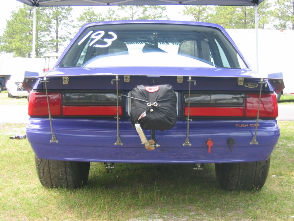 Purple 1992 Ford Mustang drag car rear view with large spoiler and drag chute