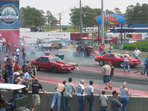 1992 Ford Mustang - Cars line up at the drag strip, with a crowd watching and a tractor in the background.