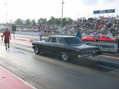1992 Ford Mustang - A classic black car races down the drag strip with a red car in the adjacent lane and spectators in the stands.