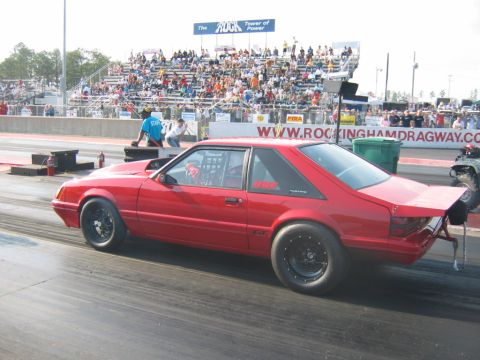 1992 Ford Mustang - A red 1992 Ford Mustang drag car is seen from the side at Rockingham Dragway, equipped with racing slicks and a roll cage.