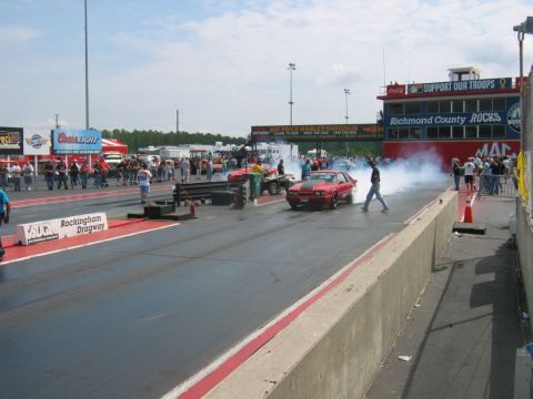 1992 Ford Mustang - A red sports car performs a burnout on the drag strip at Rockingham Dragway, creating a cloud of smoke.