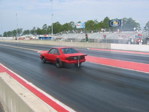 1992 Ford Mustang - A red 1992 Ford Mustang races down the drag strip, viewed from behind.