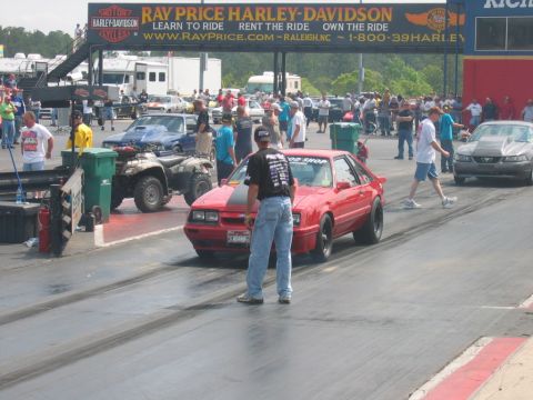 1992 Ford Mustang - Red Ford Mustang Fox Body prepares for a drag race, with other vehicles and spectators present.