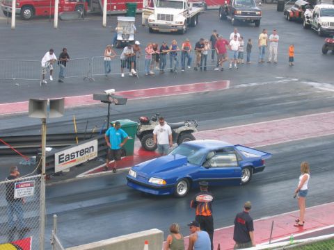 1992 Ford Mustang - A blue drag car is staged on the track with spectators in the background.