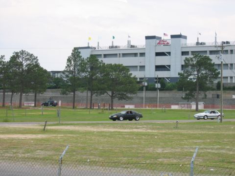 1992 Ford Mustang - A black coupe drives past a grandstand at Rockingham Dragway.
